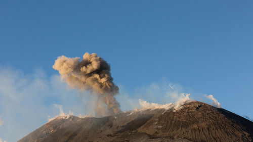 Smoke emitting from volcanic mountain against sky