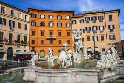 Statue by fountain in city