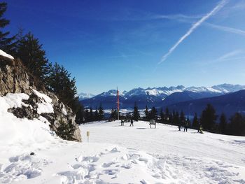 Snow covered landscape against blue sky