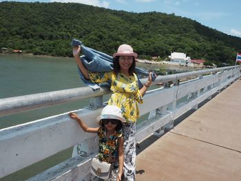 Portrait of smiling woman standing against railing