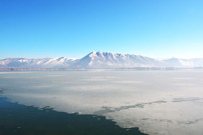 Winter landscape scene with frozen lake, snowy mountain