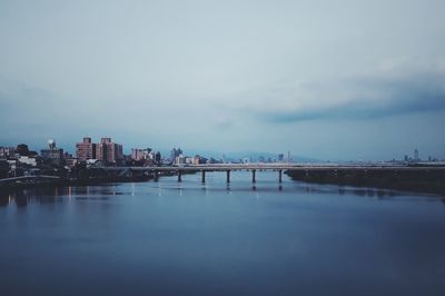 Bridge over river in city against sky