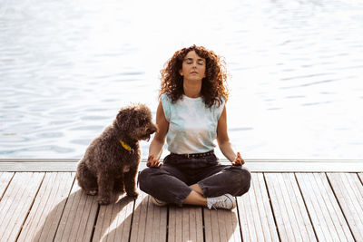 Portrait of young woman with dog on wooden floor