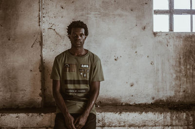 Portrait of young man standing against wall