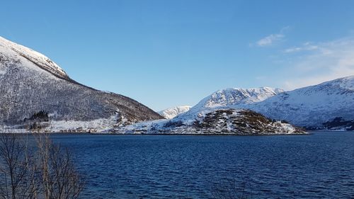 Scenic view of lake by snowcapped mountains against sky