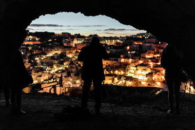 Silhouette of illuminated cityscape against sky at night