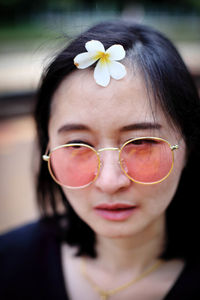 Close-up of woman with sunglasses wearing white flower