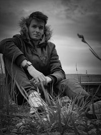 Portrait of woman sitting on field against sky