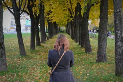 Rear view of woman standing in park during autumn