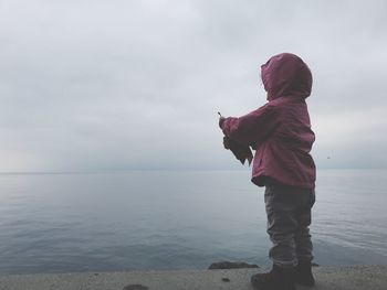 Boy standing on beach against sky