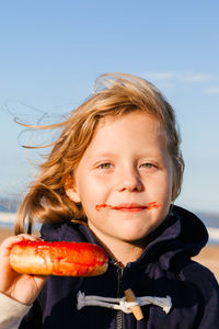 Girl in delight eats donut with red icing, food stained her mouth