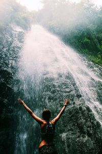 Rear view of young woman standing in water