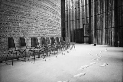 Empty chairs in snow against building