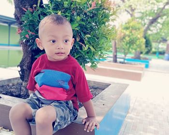 Portrait of cute boy sitting outdoors