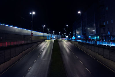 Empty road amidst illuminated street lights against clear sky at night