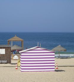 Deck chairs and parasols on beach against clear sky