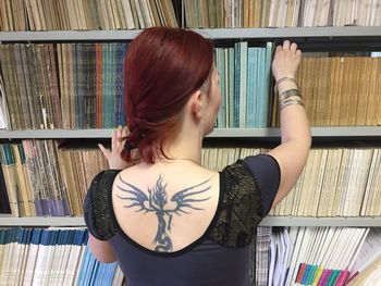 Rear view of woman selecting book from shelf