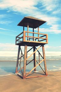 Lifeguard hut on shore at beach against sky