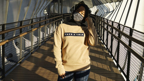 Portrait of woman wearing mask standing on footbridge