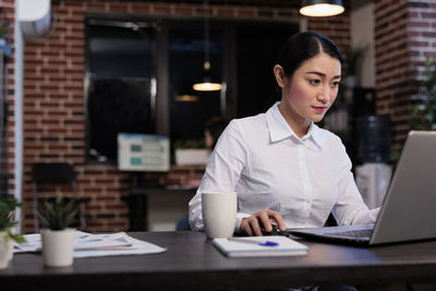 Businesswoman using laptop while sitting at office