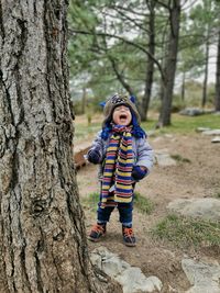 Full length baby boy shouting while standing by tree