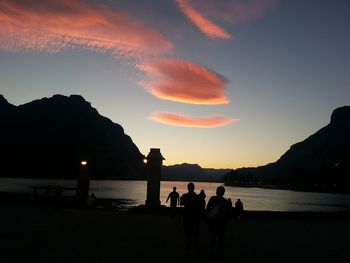 Silhouette people by sea against sky during sunset