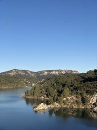 Scenic view of lake and mountains against clear blue sky