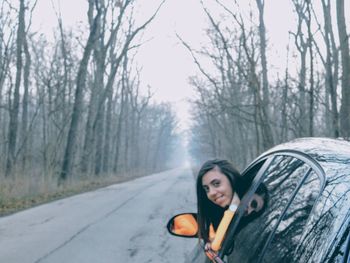 Portrait of woman on road against trees during winter