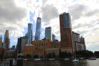 Modern buildings by river against sky in city