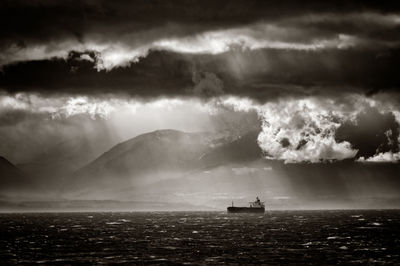 Ship in sea against cloudy sky