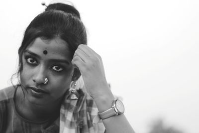 Close-up portrait of young woman wearing jewelries against clear sky