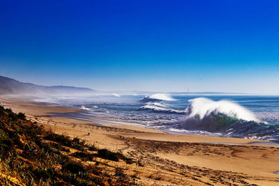 Scenic view of beach against clear blue sky