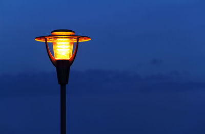 Low angle view of illuminated street light against blue sky