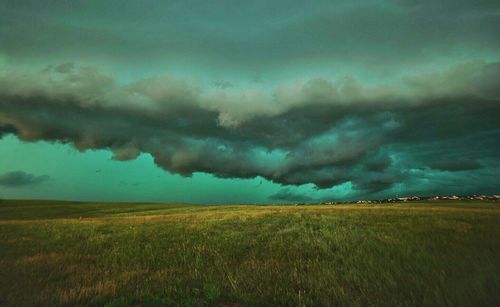 Scenic view of grassy field against cloudy sky