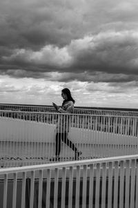 Side view of man on railing against sky