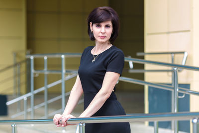 Beautiful slender middle-aged brunette in black dress on a sunny summer day.