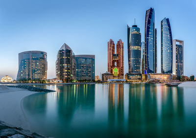 Illuminated buildings in city against clear sky