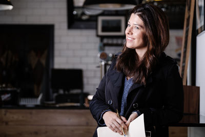 Young woman holding camera while standing at home