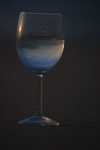 Close-up of wineglass on table against black background