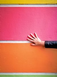Close-up of hand against red wall