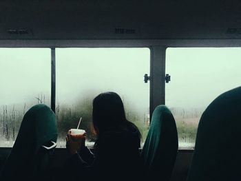 Rear view of people sitting at window