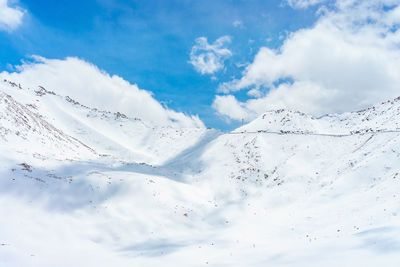 Low angle view of snowcapped mountain against blue sky