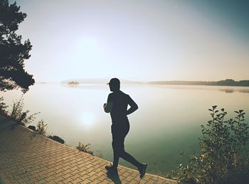 Running man wear dark running shoes and trendy sports clothes. sportsman exercising morning at bank