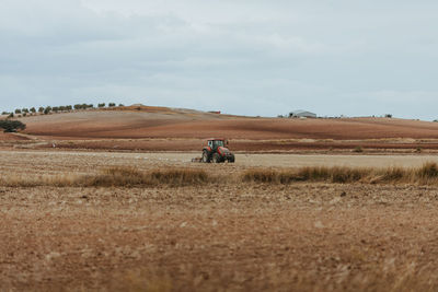 Rear view of people riding motorcycle on field against sky