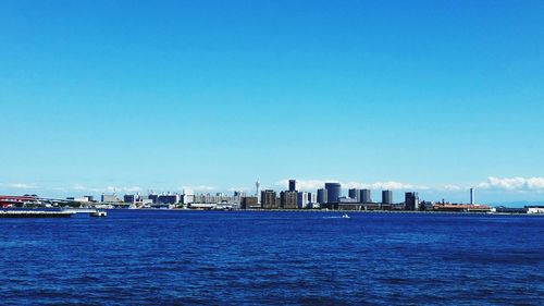 City at waterfront against blue sky