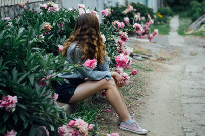 Woman standing by pink flowering plants