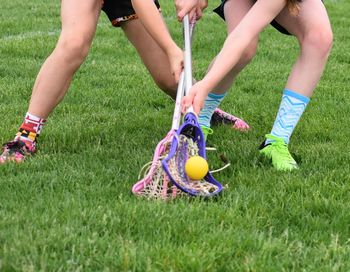 Low section of women playing lacrosse on field