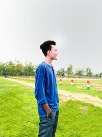 Happy boy playing soccer field against clear sky