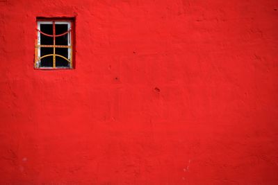 Low angle view of window on red wall