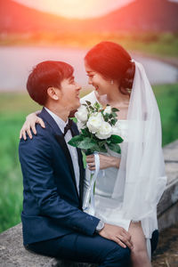 Midsection of couple holding flower bouquet